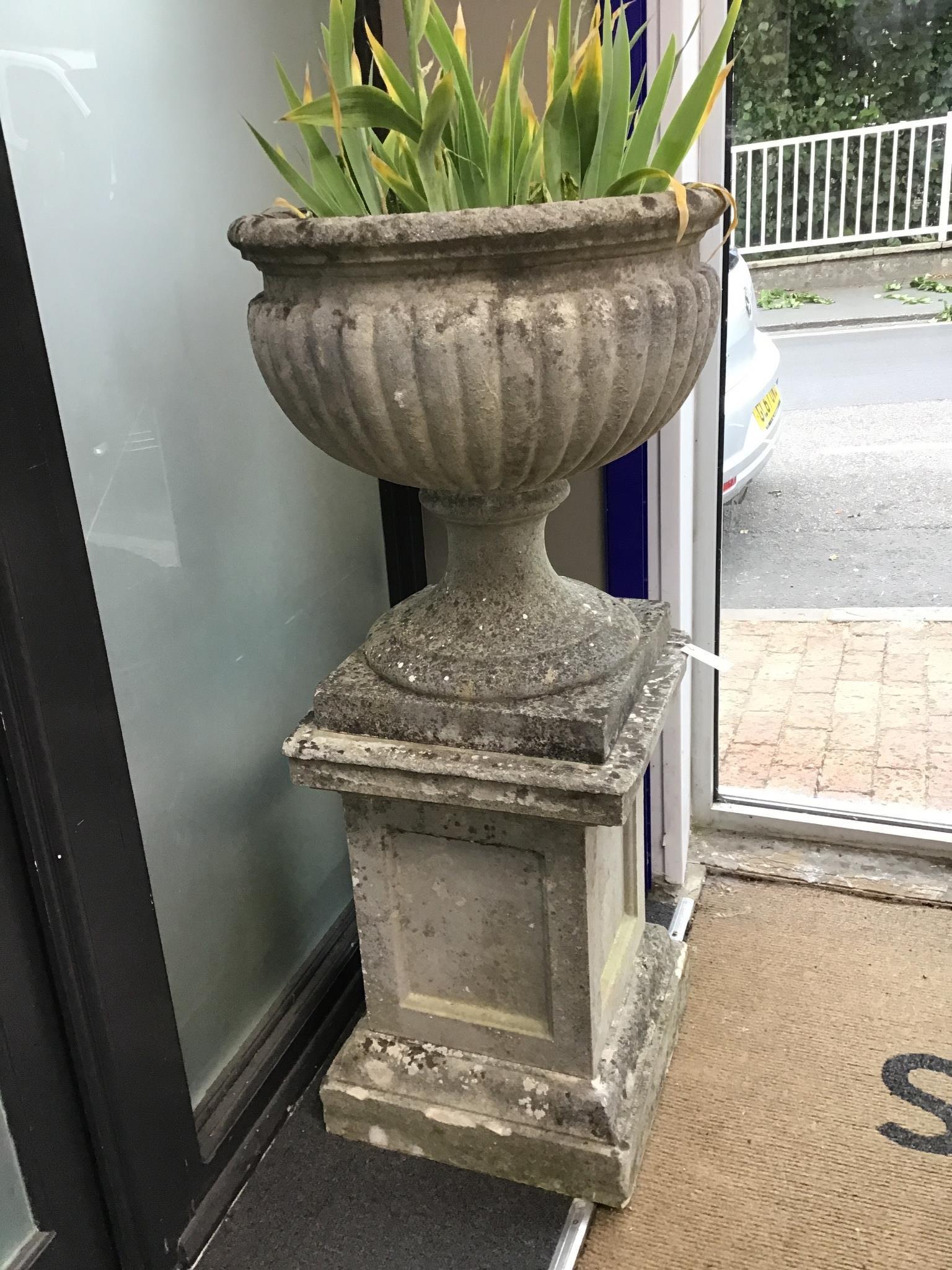 A pair of reconstituted stone campana shaped garden urns on square plinths, diameter 58cm height 129cm